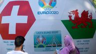 People stand by a ball advertising the upcoming Euro 2020 soccer championship displayed in Baku, Azerbaijan, Thursday, June 10, 2021. The Euro 2020 gets underway on Friday June 11 and is being played in 11 host cities across 11 countries. The event was delayed by one year after being postponed in 2020 due to the COVID-19 pandemic. (AP Photo/Darko Vojinovic)