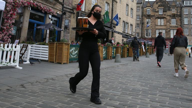 A server carries a tray of drinks from a pub in the Grassmarket in Edinburgh, as beer gardens, non-essential shops, restaurants and cafes, along with swimming pools, libraries and museums in Scotland reopen today after lockdown restrictions have eased. Picture date: Monday April 26, 2021.