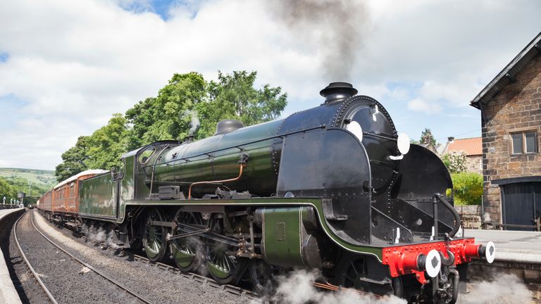 A steam locomotive gathers steam at Grosmont Station on the North York Moors Railway.
