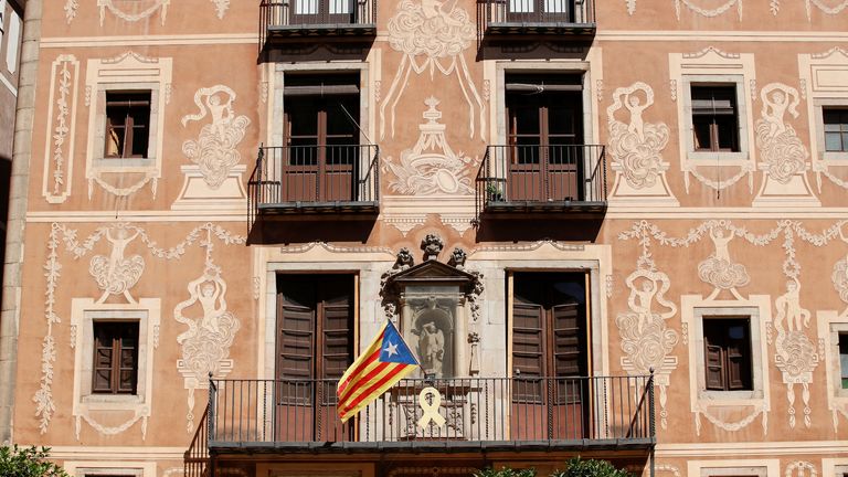 A yellow ribbon hangs from a balcony next to a Catalan separatist flag in Barcelona on Tuesday