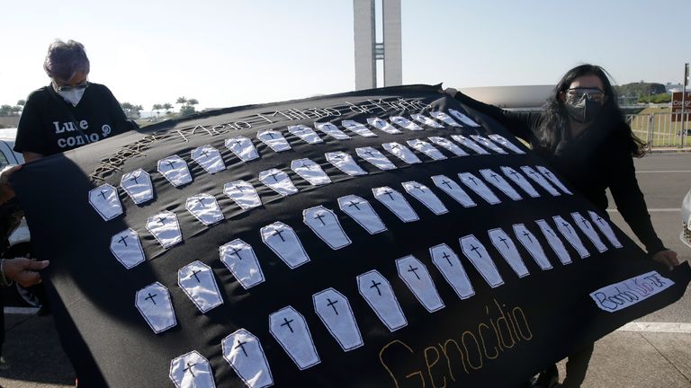 Activists display a cloth covered with small coffins and the Portuguese word for genocide outside Congress in protest of the high death toll from COVID-19. Pic AP