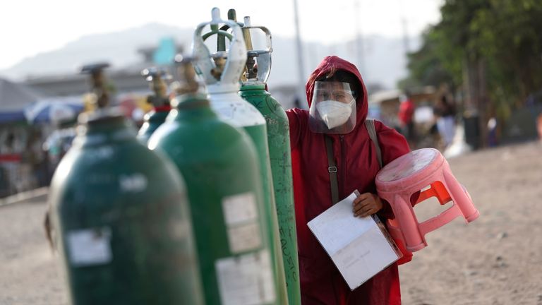 Sara Manrique checks her empty oxygen tank as she stands in line for a refill in the Villa El Salvador neighborhood of Lima. Pic: AP