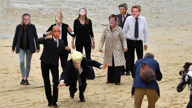 Members of the media take pictures of climate change activists wearing masks representing world leaders during a protest in St. Ives, on the sidelines of G7 summit in Cornwall, Britain, June 11, 2021. REUTERS/Dylan Martinez
