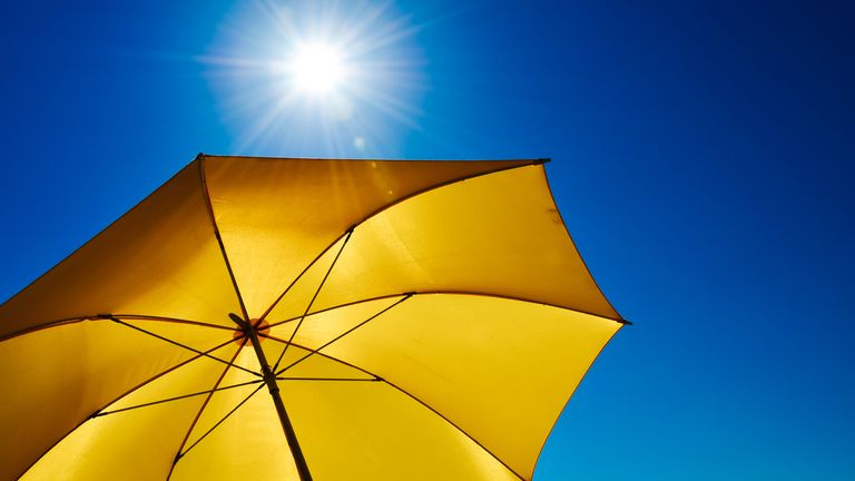 Yellow Umbrella With Bright Sun And Blue Sky stock photo