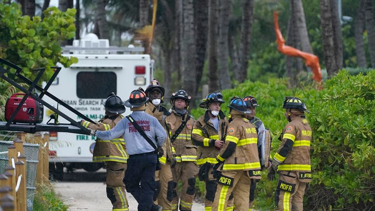 Firefighters unload a truck near the remains of the partially collapsed buildin