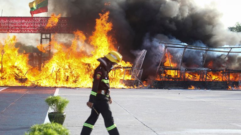 A firefighter walks past while smokes and flames billow from burning of illegal narcotics during a destruction ceremony on the outskirts of Yangon, Myanmar, Saturday, June 26, 2021. Myanmar burned over US$ 680 million worth of assorted drugs seized around the country on Saturday to commemorate the International Day against Drug Abuse and Illicit Trafficking. (AP Photo/Thein Zaw)