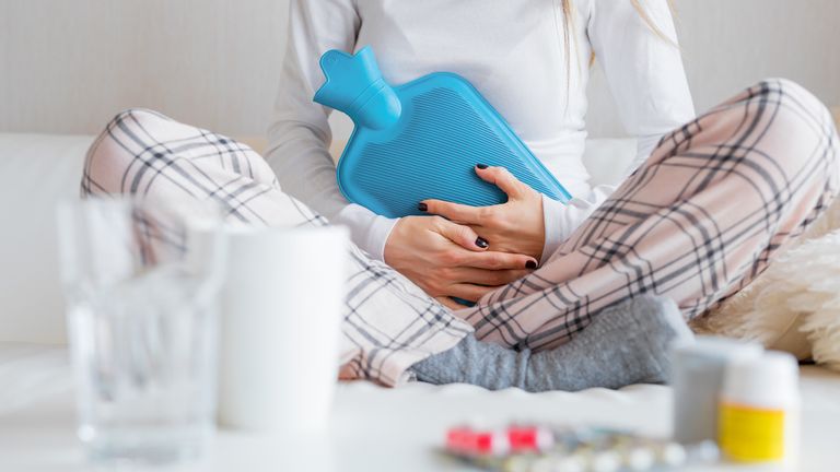 Woman with hot water bottle healing stomach pain