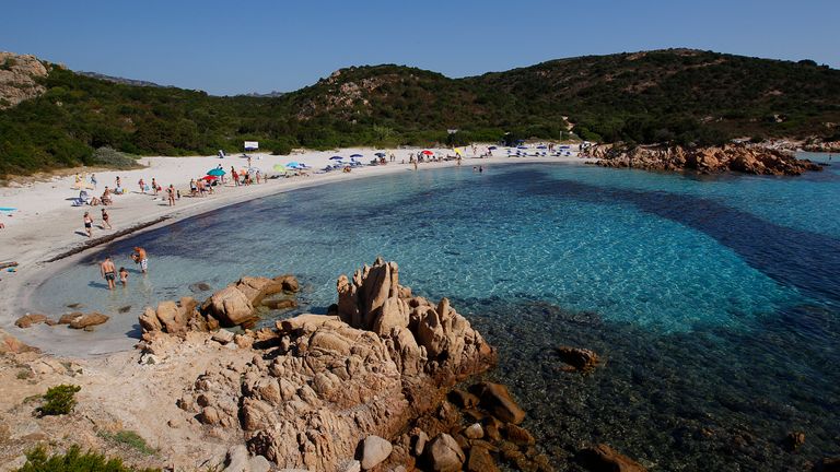 People stand at the Ramizzo beach in the so called "Emerald Coast" of the Sardinia island in Italy July 7, 2011