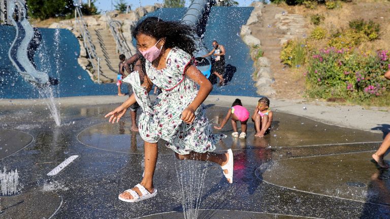 A girl jumps across a sprinkler at Jefferson Park in Seattle