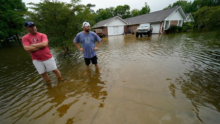 Danny Gonzales, right, stands in front of his flooded house with his neighbor Bob Neal, upset with power company trucks driving though the flooded neighborhood pushing water back into his home, after Tropical Storm Claudette passed through, in Slidell, La., Saturday, June 19, 2021. (AP Photo/Gerald Herbert)