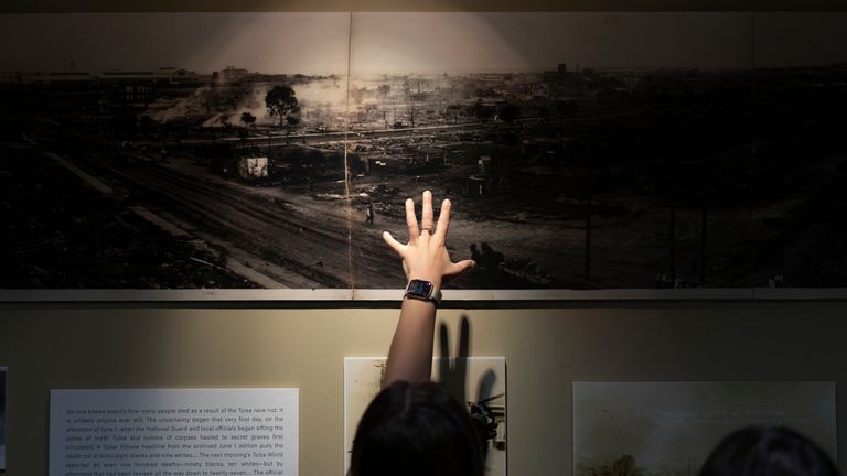 A woman points at a picture of devastation from the Tulsa Race Massacre in a prayer room at the First Baptist Tulsa church
