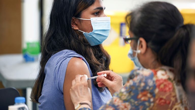 A person receives a dose of the Pfizer BioNTech vaccine at a vaccination centre for those aged over 18 years old at the Belmont Health Centre in Harrow