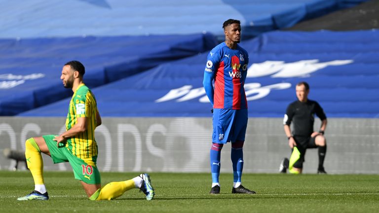 Wilfried Zaha stands while other players take a knee in March