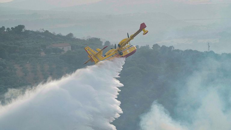 Sebuah pesawat Canadair menjatuhkan air untuk memadamkan api, dekat Oristano, di pulau Sardinia, Italia, Senin, 26 Juli 2021. Kebakaran berkobar pada hari Minggu di pulau Sardinia Mediterania Italia, di mana hampir 400 orang dievakuasi semalam.  Tidak ada korban jiwa atau cedera yang dilaporkan.  Petugas pemadam kebakaran mengatakan beberapa rumah rusak di wilayah pedalaman barat pulau itu.  (Alessandro Tocco / LaPresse melalui AP)