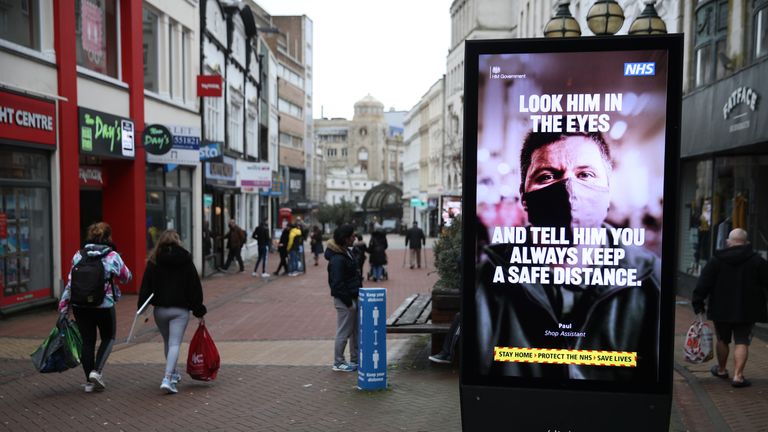People make their way past a government coronavirus sign on Old Christchurch road in Bournemouth, Dorset, during England's third national lockdown to curb the spread of coronavirus. Picture date: Tuesday February 16, 2021.