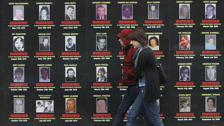 Two women walk past mural depicting victims of the troubles in west Belfast as talks continue on transferring policing and justice powers from London to Belfast