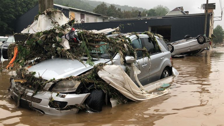 Damaged cars and debris in a flooded street in Pepinster, Belgium