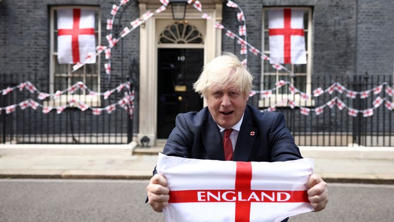 Britain's Boris Johnson poses on Downing Street with a flag ahead of the Euro 2020 final, in London, Britain July 9, 2021. REUTERS/Henry Nicholls