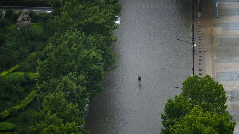 Eine Person geht in der durch einen Regenschauer verursachten Staunässe in Zhengzhou, der zentralchinesischen Provinz Henan, 20. Juli 2021 (Imaginechina über AP Images) spazieren.
