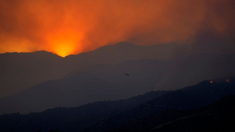 A helicopter flies towards the smoke over fire in the Larnaca mountain region on Saturday, July 3, 2021. Cyprus has asked fellow European Union member states on Saturday to help battle a huge fire in a mountainous region of the east Mediterranean island nation that has forced the evacuation of at least three villages. (AP Photo/Petros Karadjias)