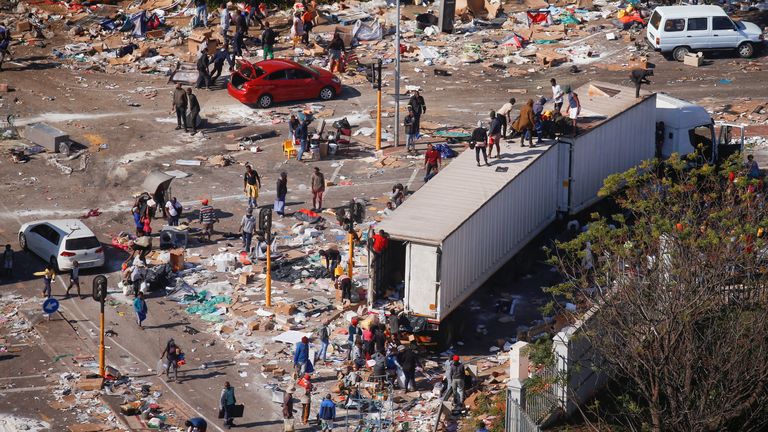 People loot an area near a burning warehouse after violence erupted following the jailing of former South African President Jacob Zuma, in Durban, South Africa, July 14, 2021. REUTERS/Rogan Ward