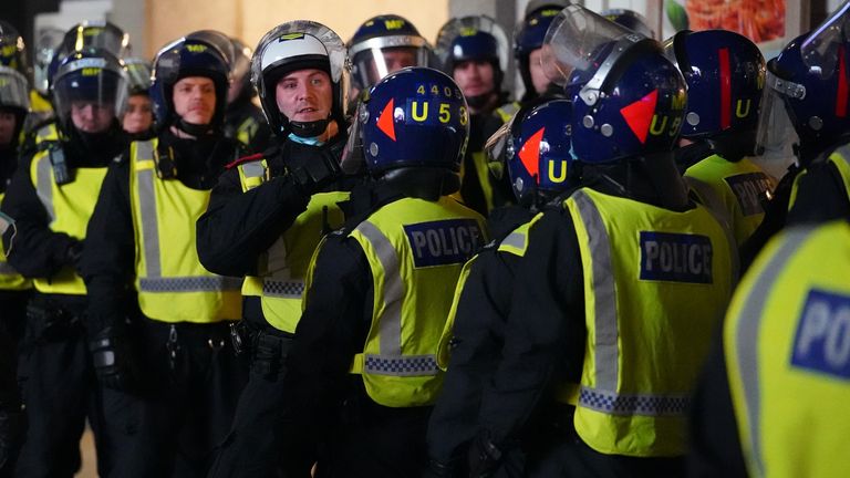 La police anti-émeute observe les fans anglais célébrer à Piccadilly Circus, dans le centre de Londres, après que l'Angleterre se soit qualifiée pour la finale de l'Euro 2020, remportant leur match de demi-finale contre le Danemark.  Photo date : mercredi 7 juillet 2021.