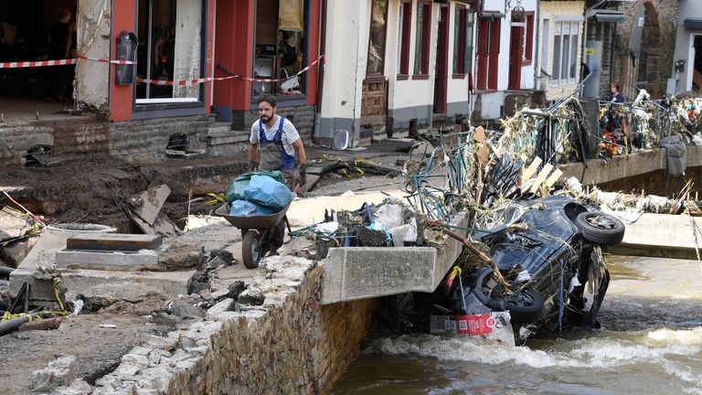 dpatop - 17 July 2021, North Rhine-Westphalia, Bad M..nstereifel: A helper carries rubbish and debris along the Erft. In the night of 15.07.2021, the Erft floods totally devastated the historic core of the city. Streets and shops were flooded. Gas, electricity and telephone lines were exposed. Photo: Roberto Pfeil/dpa