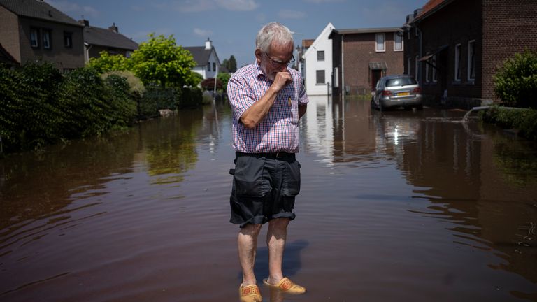 Wiel de Bie, 75, stands outside his flooded home in the town of Brommelen, Netherlands, Saturday, July 17, 2021. In the southern Dutch province of Limburg, which also has been hit hard by flooding, troops piled sandbags to strengthen a 1.1-kilometer (0.7 mile) stretch of dike along the Maas River, and police helped evacuate low-lying neighborhoods. (AP Photo/Bram Janssen)      