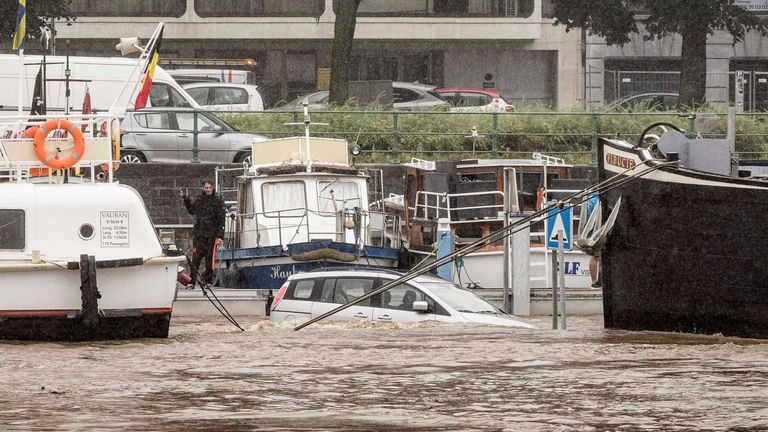 Un'auto è sommersa tra due barche nel fiume Mosa durante un'inondazione a Liegi, in Belgio.  Pic: AP