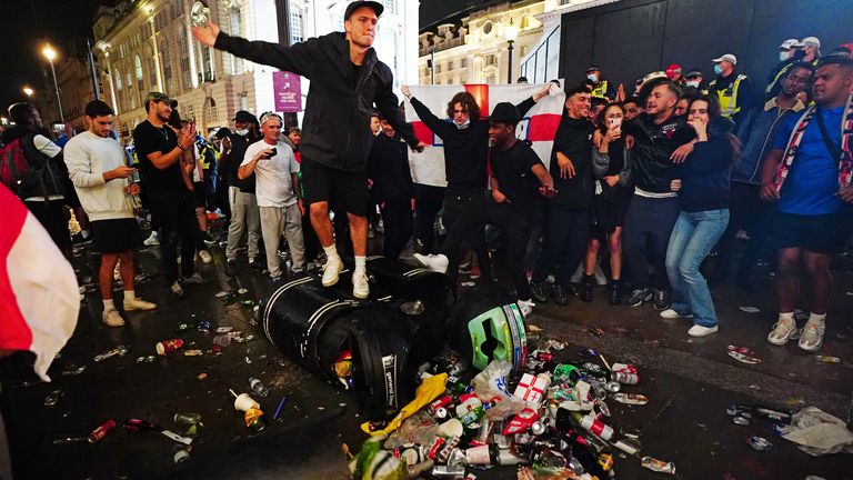 English fans kick and stand on a litter bin in Piccadilly Circus following the match