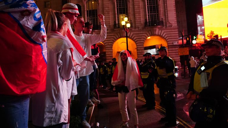 England fans stand against a line of police in Piccadilly Circus