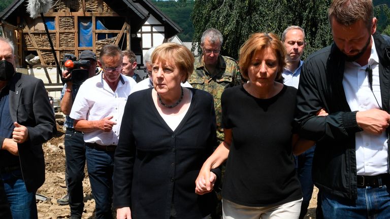 German Chancellor Angela Merkel held hands with local politicians in the flood-hit village of Schuld. Pic: AP