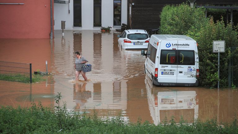 A woman wades across floodwater in Gross-Vernich, North Rhine-Westphalia, Germany