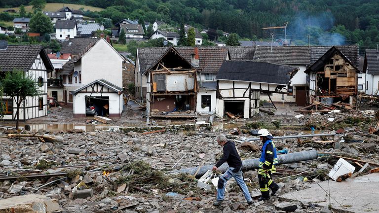 A man and firefighter walk through debris, following heavy rainfalls in Schuld, Germany
