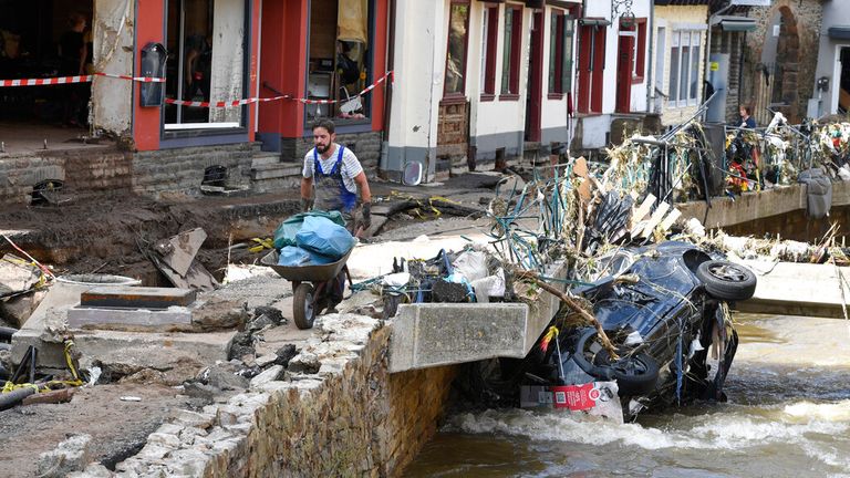 Ein Mann trägt in Bad Münsterifel Müll über den Fluss Erbt.  Bild: Abby