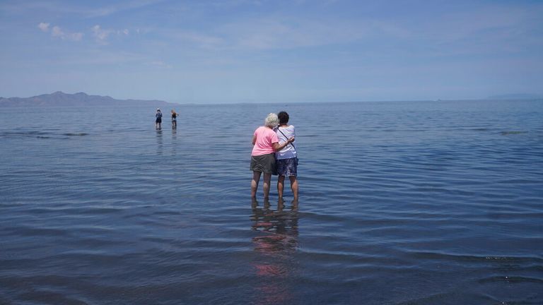Visitors stand in the shallow waters of the Great Salt Lake 