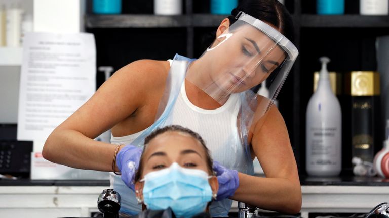 A hairdresser wearing a face shield washes the hair of a client at Ever After Hair, Beauty & Aesthetics, after it reopened following the outbreak of the coronavirus disease (COVID-19), in Newport Pagnell, Britain, July 14, 2020