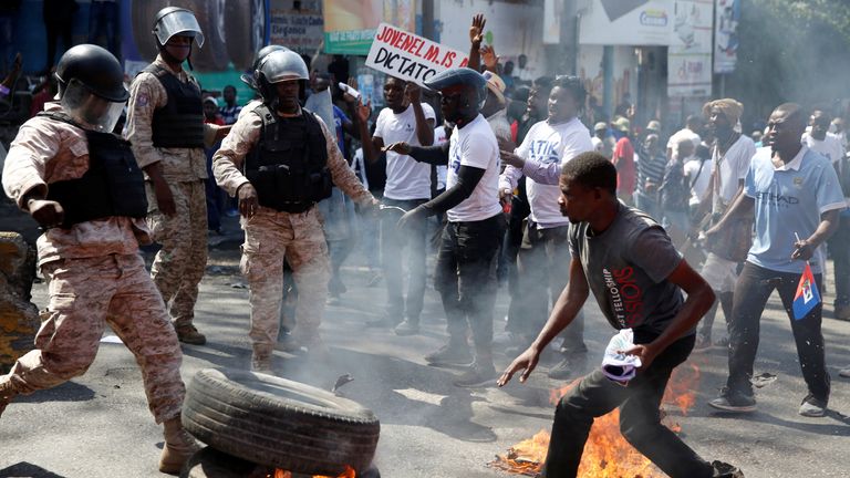 Barricades burn in Haiti in protest against President Jovenel Moise
Police officers look on as demonstrators take part in a march during a protest against Haiti&#39;s President Jovenel Moise, in Port-au-Prince, Haiti February 14, 2021. REUTERS/Jeanty Junior Augustin