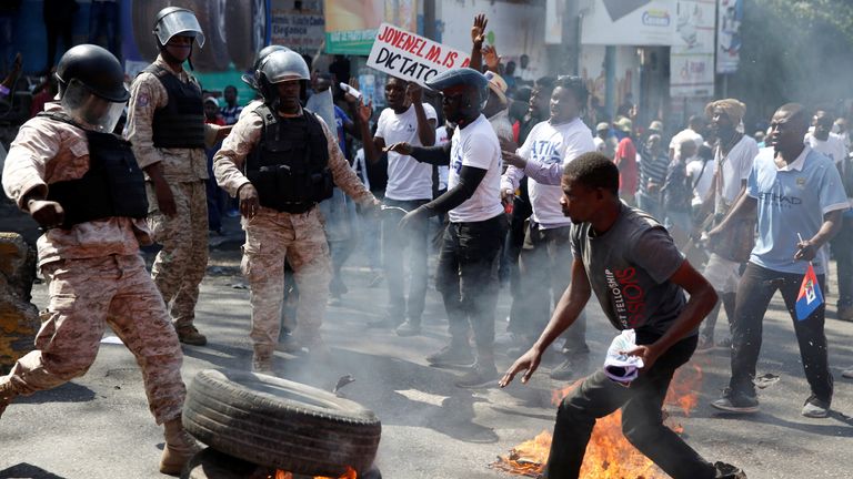 Absperrungen brennen in Haiti aus Protest gegen Präsident Jovenel Moise Polizisten betrachten Demonstranten, die an einer Kundgebung während eines Protests gegen den haitianischen Präsidenten Jovenel Moise in Port-au-Prince, Haiti, 14. Februar 2021 teilnehmen. REUTERS/Ginty Jr. Augustin