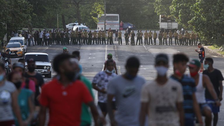 Demonstrators walk away from army soldiers blocking a road in Havana