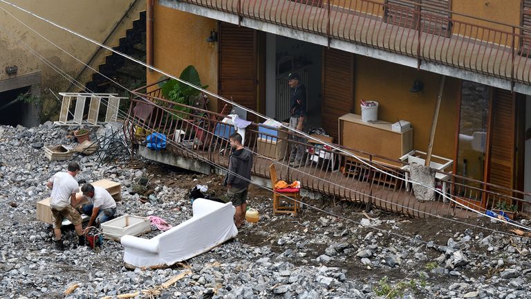 Orang-orang bekerja setelah tanah longsor menghantam rumah setelah hujan lebat menyebabkan banjir