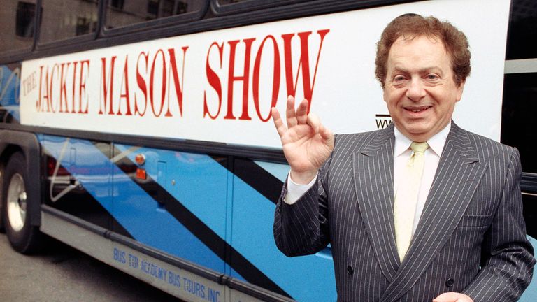 Actor/comedian Jackie Mason in 1992 standing beside a bus displaying a sign advertising his TV show, 1992. (AP Photo)