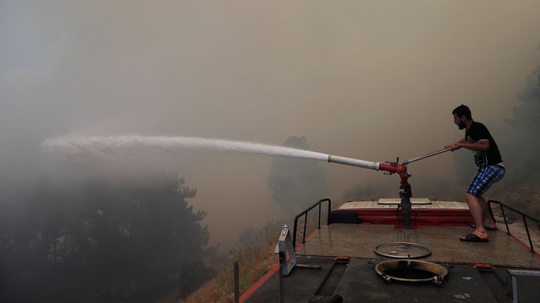 A man sprays water canon to extinguish forest fire, at Qobayat village, in the northern Akkar province, Lebanon, Thursday, July 29, 2021. Lebanese firefighters are struggling for the second day to contain wildfires in the country&#39;s north that have spread across the border into Syria, civil defense officials in both countries said Thursday. (AP Photo/Hussein Malla)


