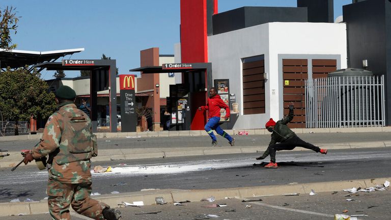 A soldier apprehends looters at a shopping centre as violence escalates