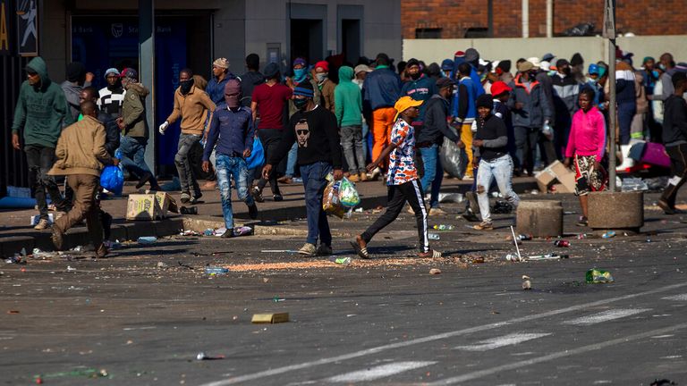 Looters carry items at Letsoho Shopping Centre in Katlehong, east of Johannesburg