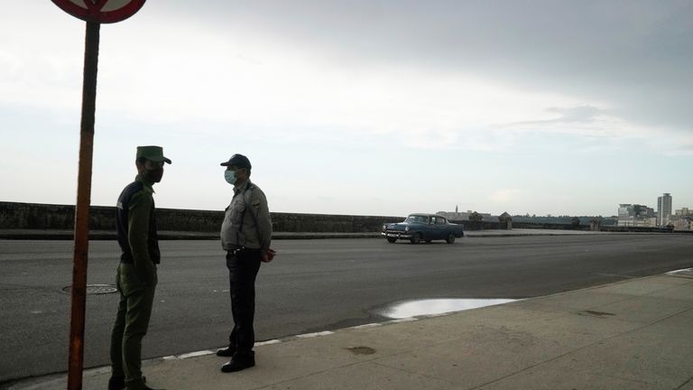 A police officer and an army soldier stand at the seafront Malecon in Havana