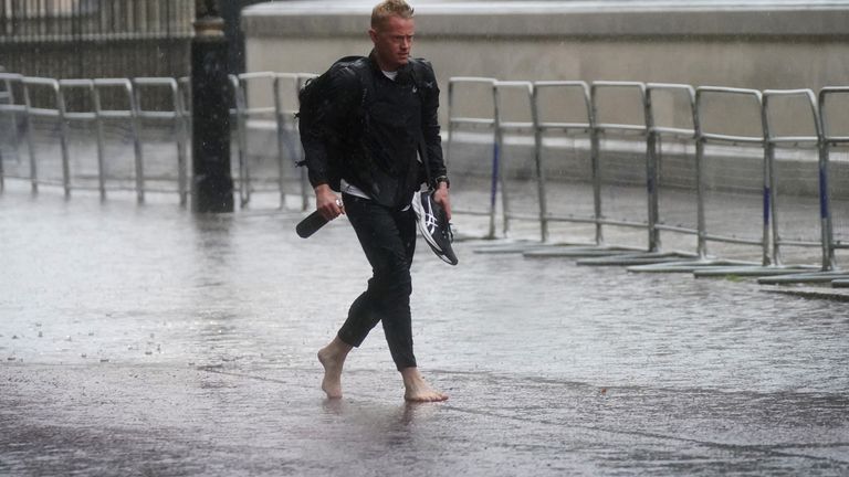 One gentleman thought it would be a good idea to take his shoes off as larges puddles formed in central London