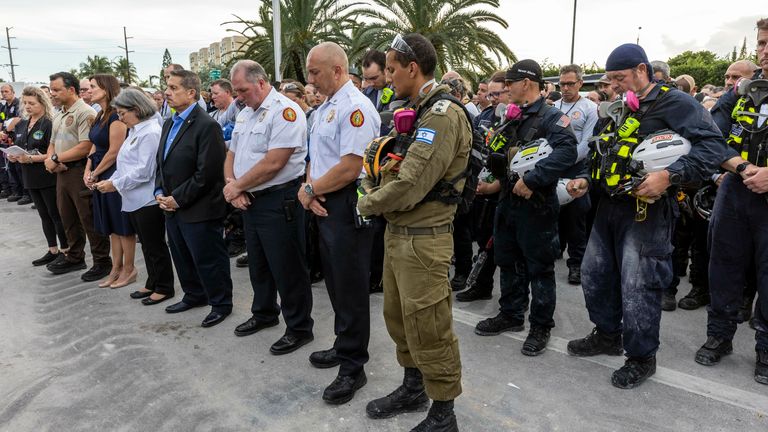 Surfside, Florida, July 7, 2021 -  Mimai-Dade County officials, members of search and rescue teams and Miami-Dade Fire Rescue along with police and workers who have been working at the site of the collapse gathered for a moment of prayer and silence in front of the rubble at the site of the building collapse