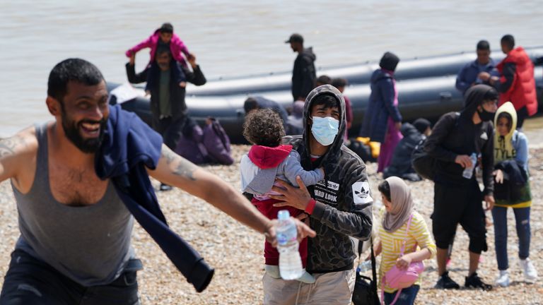 People thought to be migrants make their way up the beach after arriving on a small boat at Dungeness in Kent. Picture date: Monday July 19, 2021.