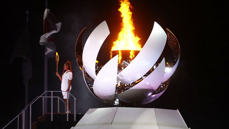 Naomi Osaka of Japan holds the Olympic torch after lighting the Olympic cauldron